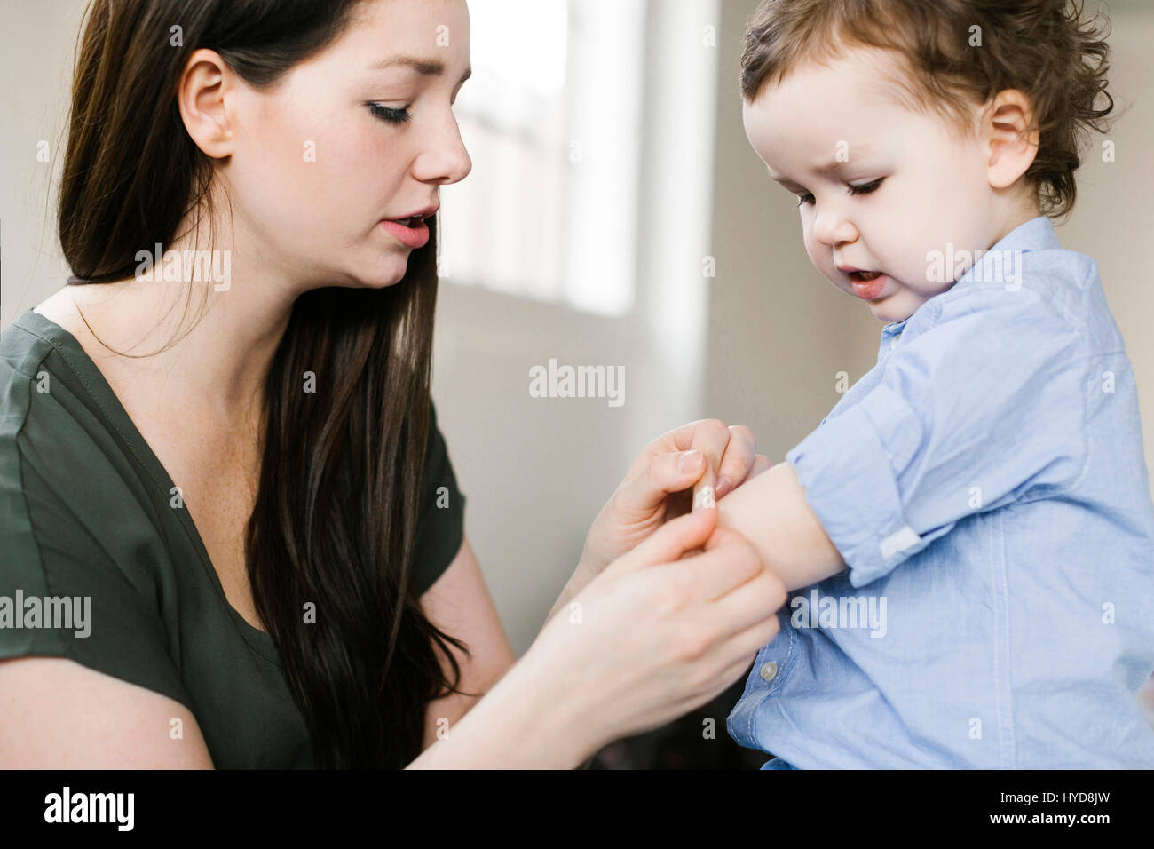 Mutter, die Gips auf den Arm des Sohnes (4-5) anwendet Stockfoto
