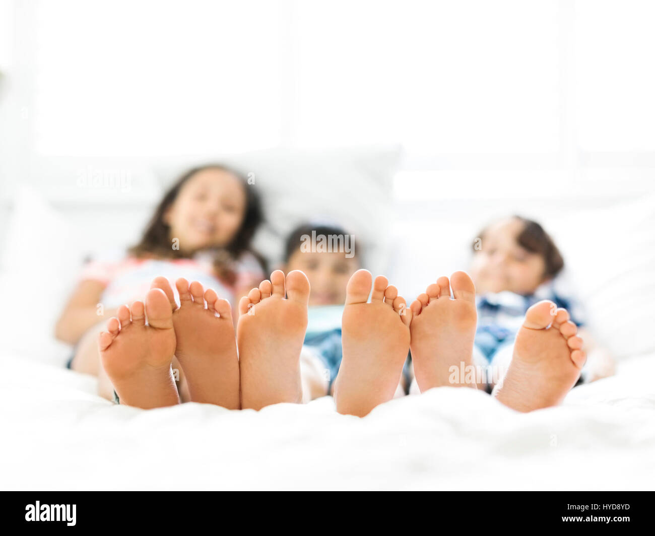 Geschwister (10-11, 6-7, 8-9) liegen nebeneinander im Bett Stockfoto