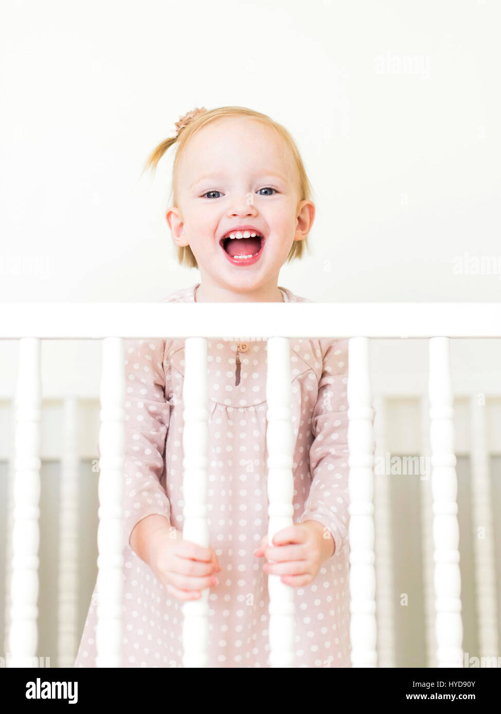 Inhalt kleines Mädchen ( 12-17 Monate) Mit offenem Mund in der Krippe stehend Stockfoto