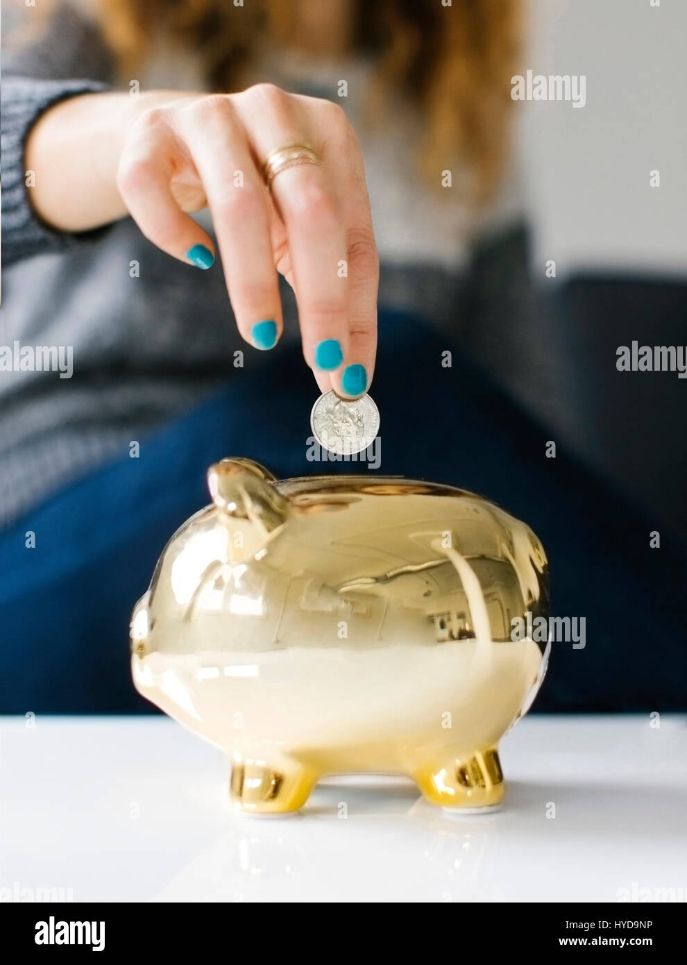 Frau fällt Münze in Gold Sparschwein Stockfoto