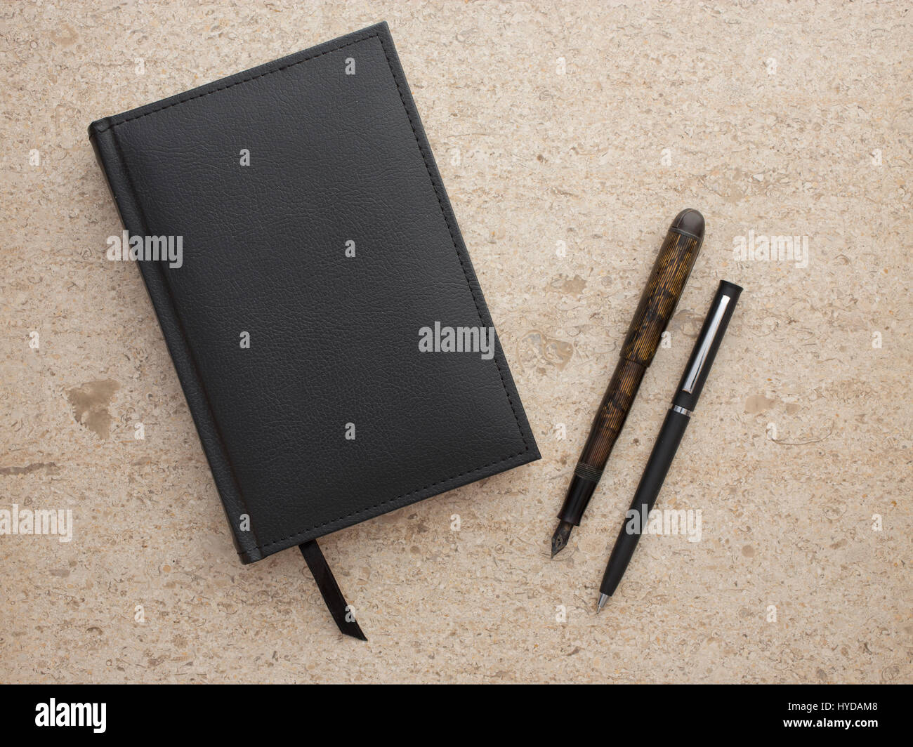 Studioaufnahme eines schwarzen Notizbuchs und zwei Stiften Stockfoto
