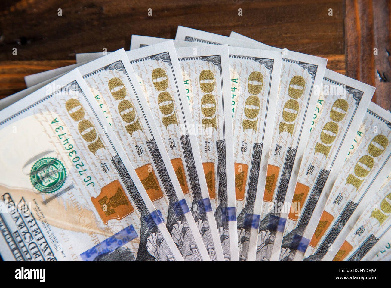 Ein Stapel von ganz neuen Hundert-Euro-Scheine in US-Währung schwärmten aus, auf einem dunkelbraunen hölzernen Tisch Stockfoto