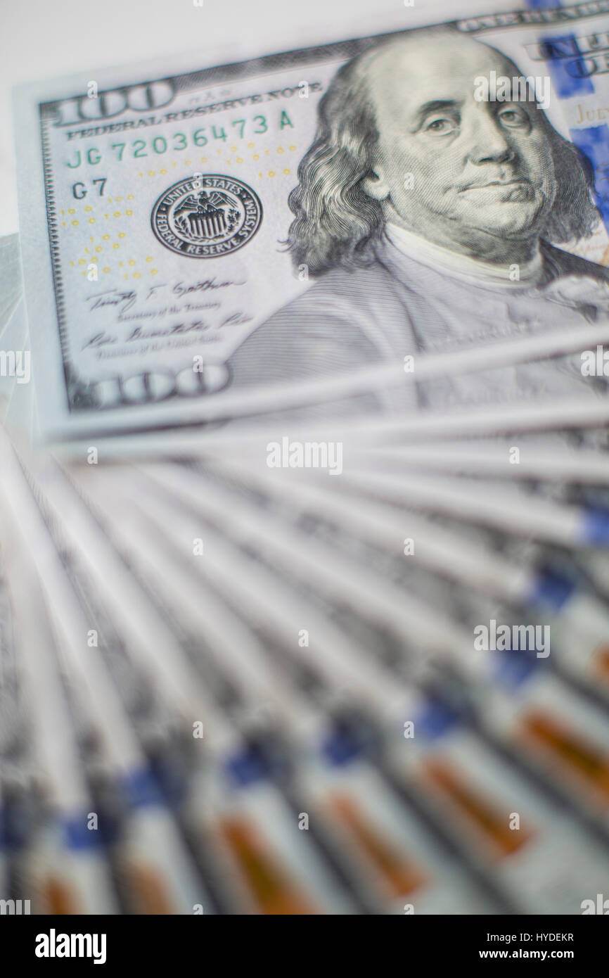 Ein Stapel von ganz neuen Hundert-Euro-Scheine in US-Währung schwärmten aus, auf einem dunkelbraunen hölzernen Tisch Stockfoto