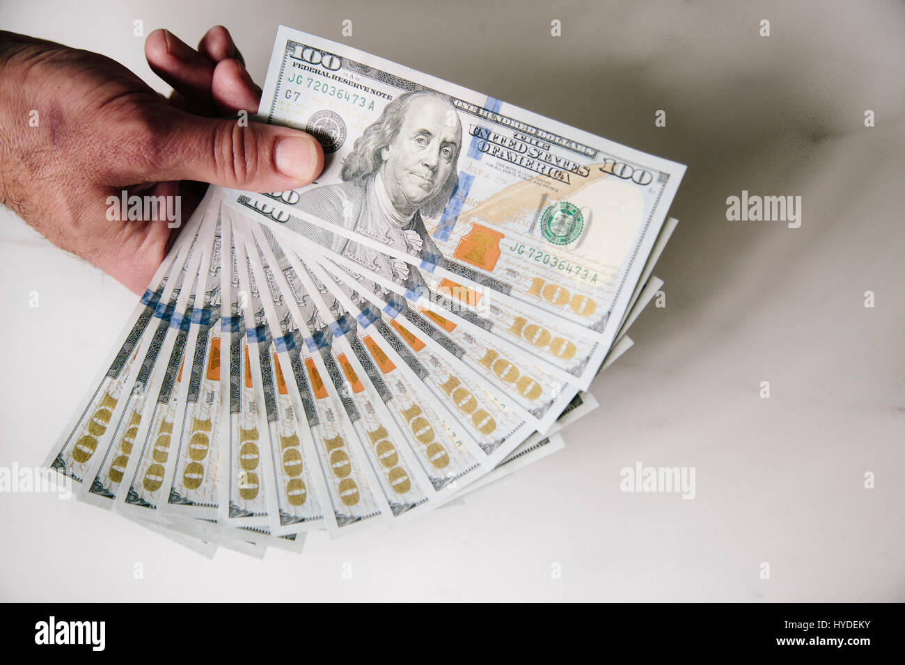 Ein Mann mit einer Hand zu Lüfter aus einem Stapel von ganz neuen Hundert-Euro-Scheine in US-Währung Stockfoto