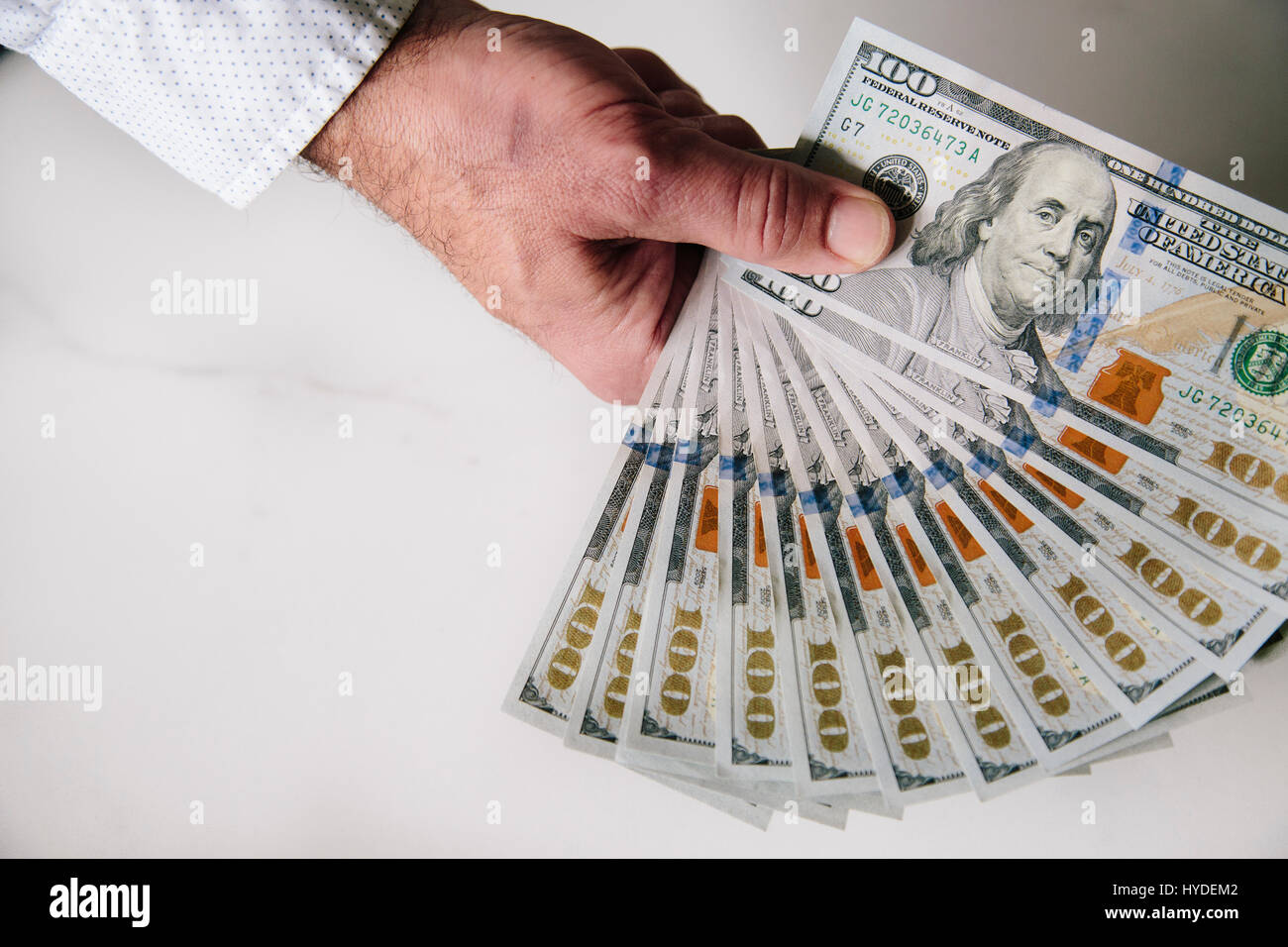 Ein Mann mit einer Hand zu Lüfter aus einem Stapel von ganz neuen Hundert-Euro-Scheine in US-Währung Stockfoto