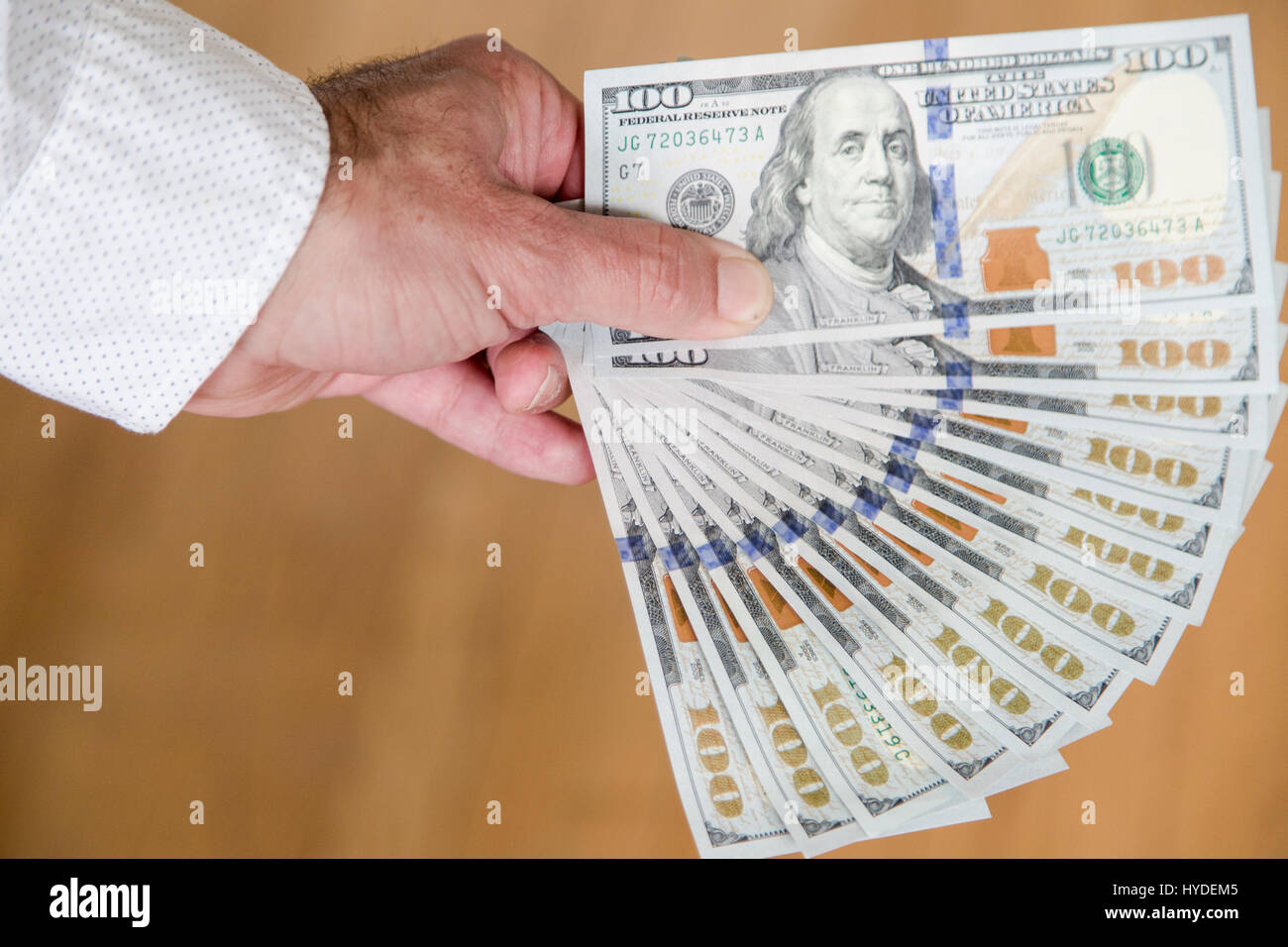 Ein Mann mit einer Hand zu Lüfter aus einem Stapel von ganz neuen Hundert-Euro-Scheine in US-Währung Stockfoto