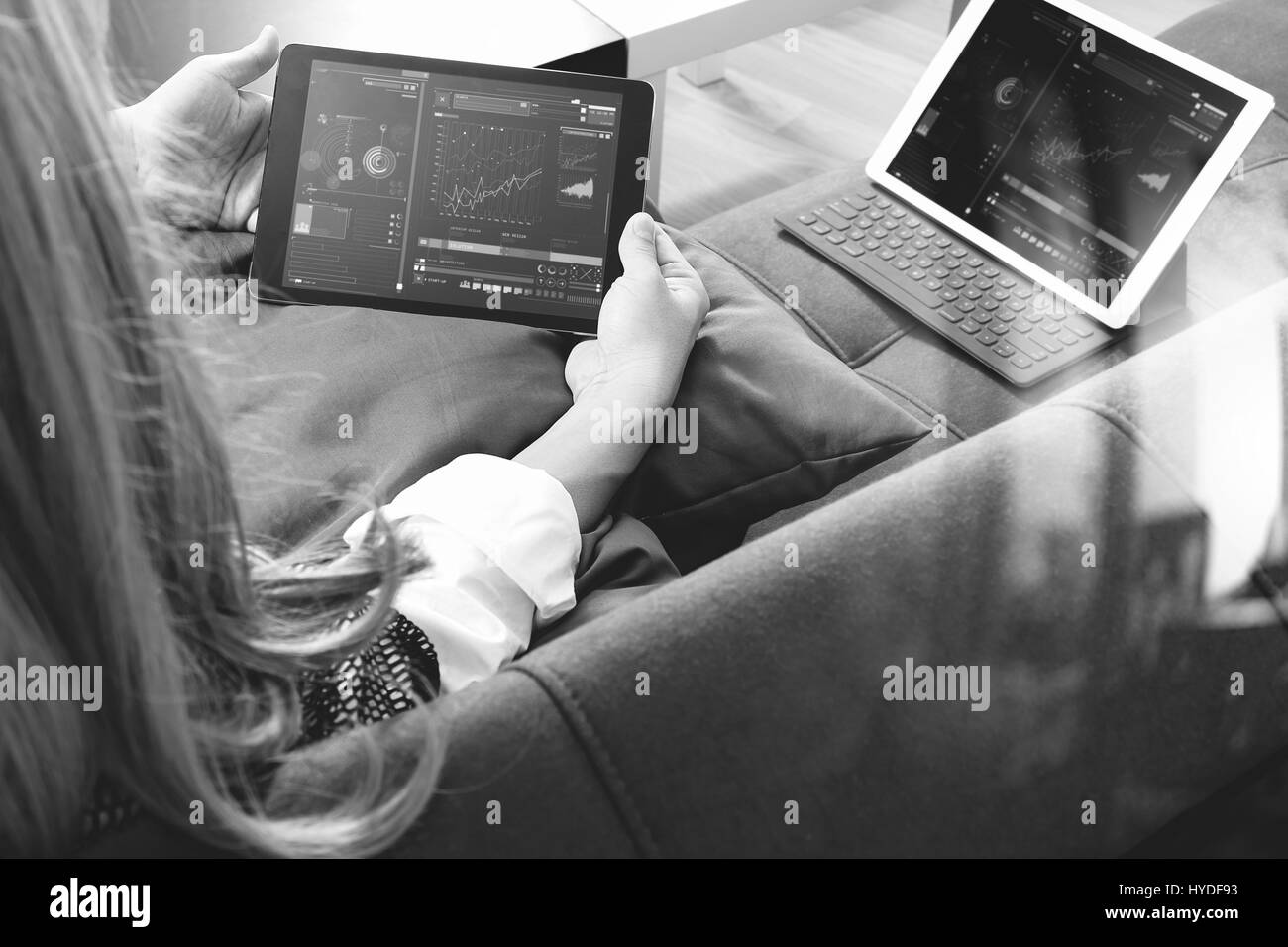 Brünette Frau mit digitalen Talet und Laptop-Computer auf Sofa im Wohnzimmer, schwarz / weiß Stockfoto