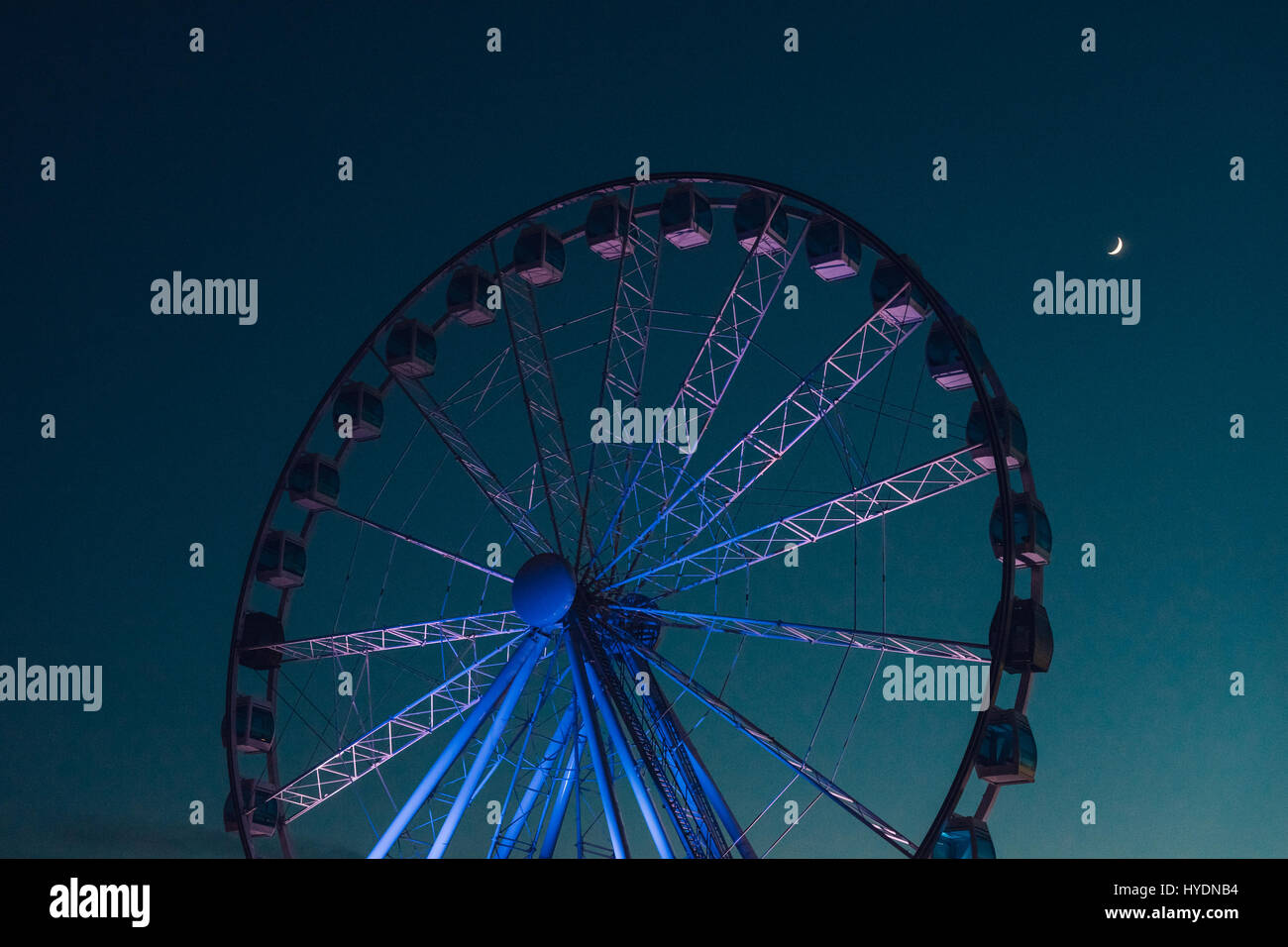 Inaktive Riesenrad vor dunklen Abendhimmel mit Halbmond Stockfoto