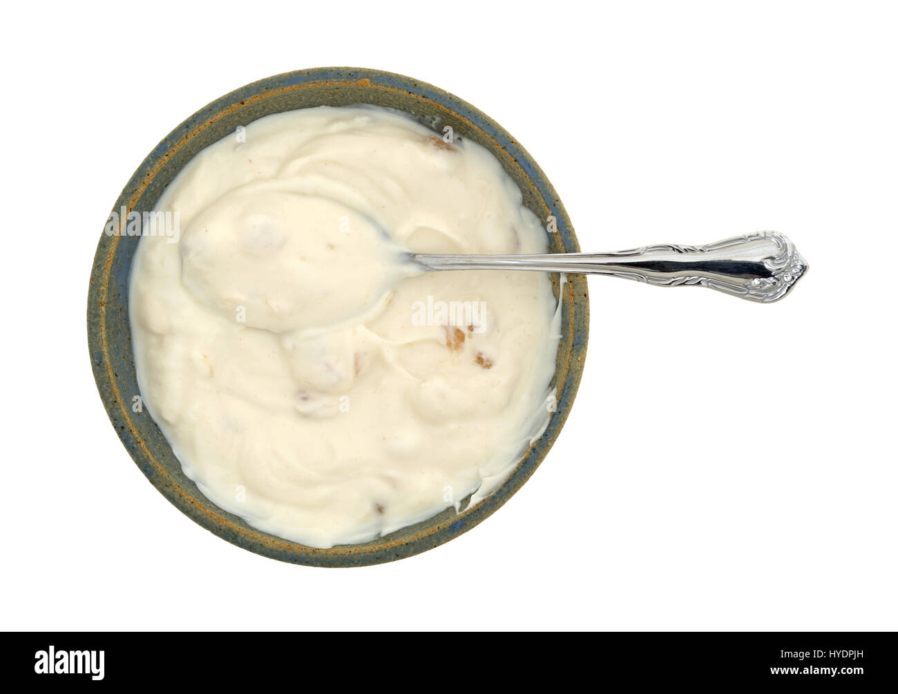 Draufsicht der Apfel Vanille Joghurt in ein altes Steingut-Schüssel mit einem Löffel in die Speisen auf einem weißen Hintergrund isoliert. Stockfoto