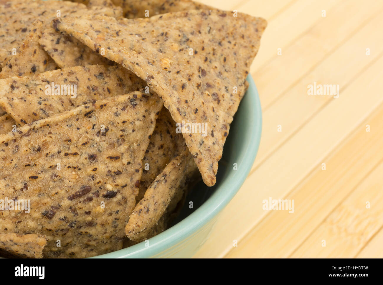 Enge Seitenansicht einer Schüssel gefüllt mit Salz und Pfeffer gewürzte Bohnen und Reis Chips auf einem Holz-Platz-Matte. Stockfoto
