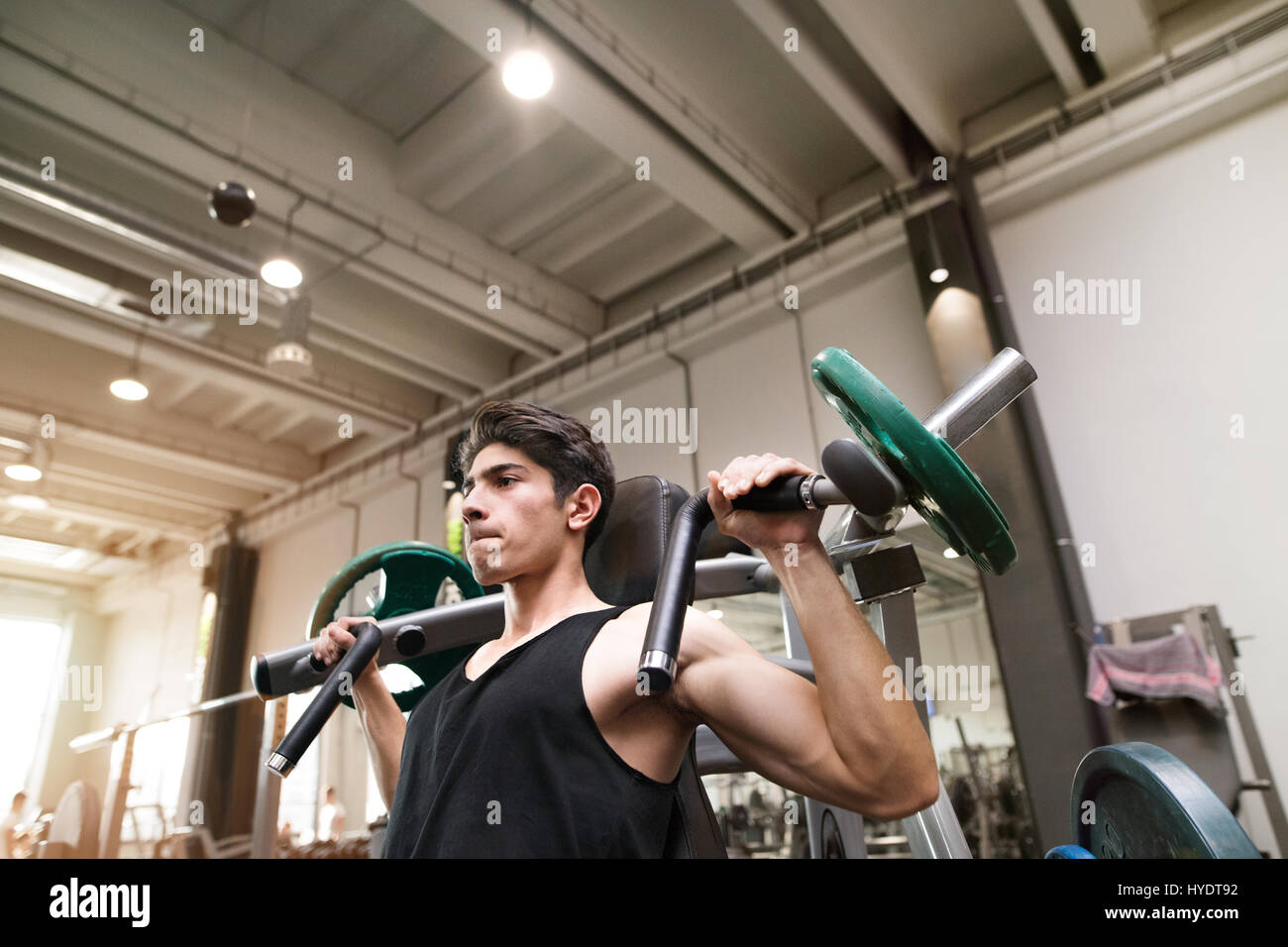Hispanic Mann training im Fitness-Studio, Schulterpresse Maschine zu tun. Stockfoto