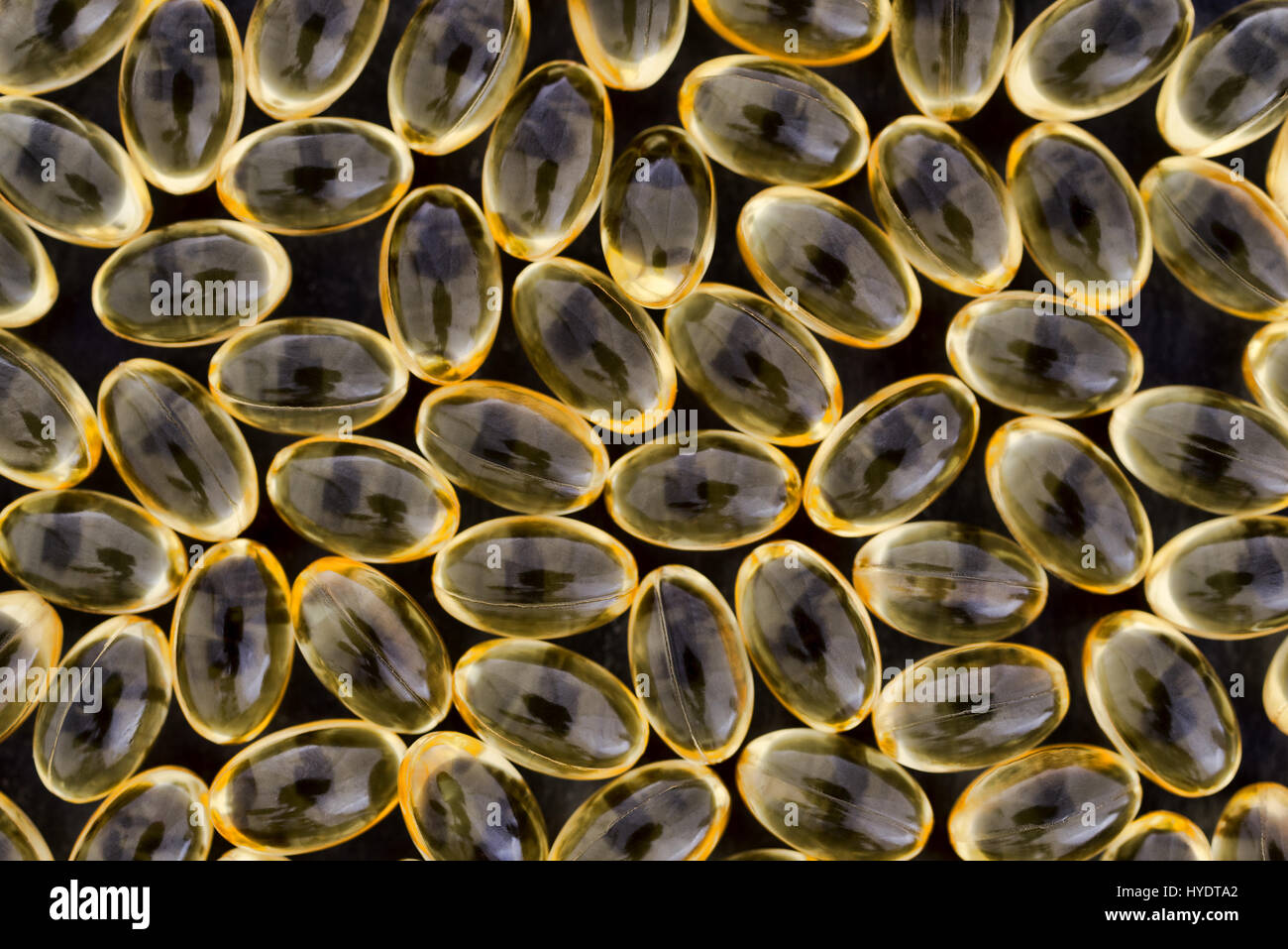 Draufsicht auf eine Gruppe von Vitamin-A-Gel-Kapseln auf einem schwarzen Hintergrund. Stockfoto