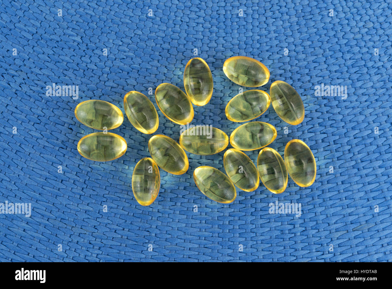 Draufsicht auf eine Gruppe von Vitamin-A-Gel-Kapseln auf blauem Hintergrund gewebt. Stockfoto