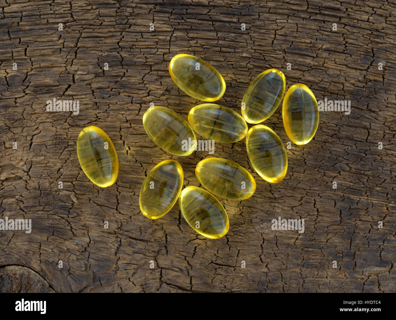 Draufsicht auf eine Gruppe von Vitamin-A-Gel-Kapseln auf eine alte braune Holzplatte. Stockfoto