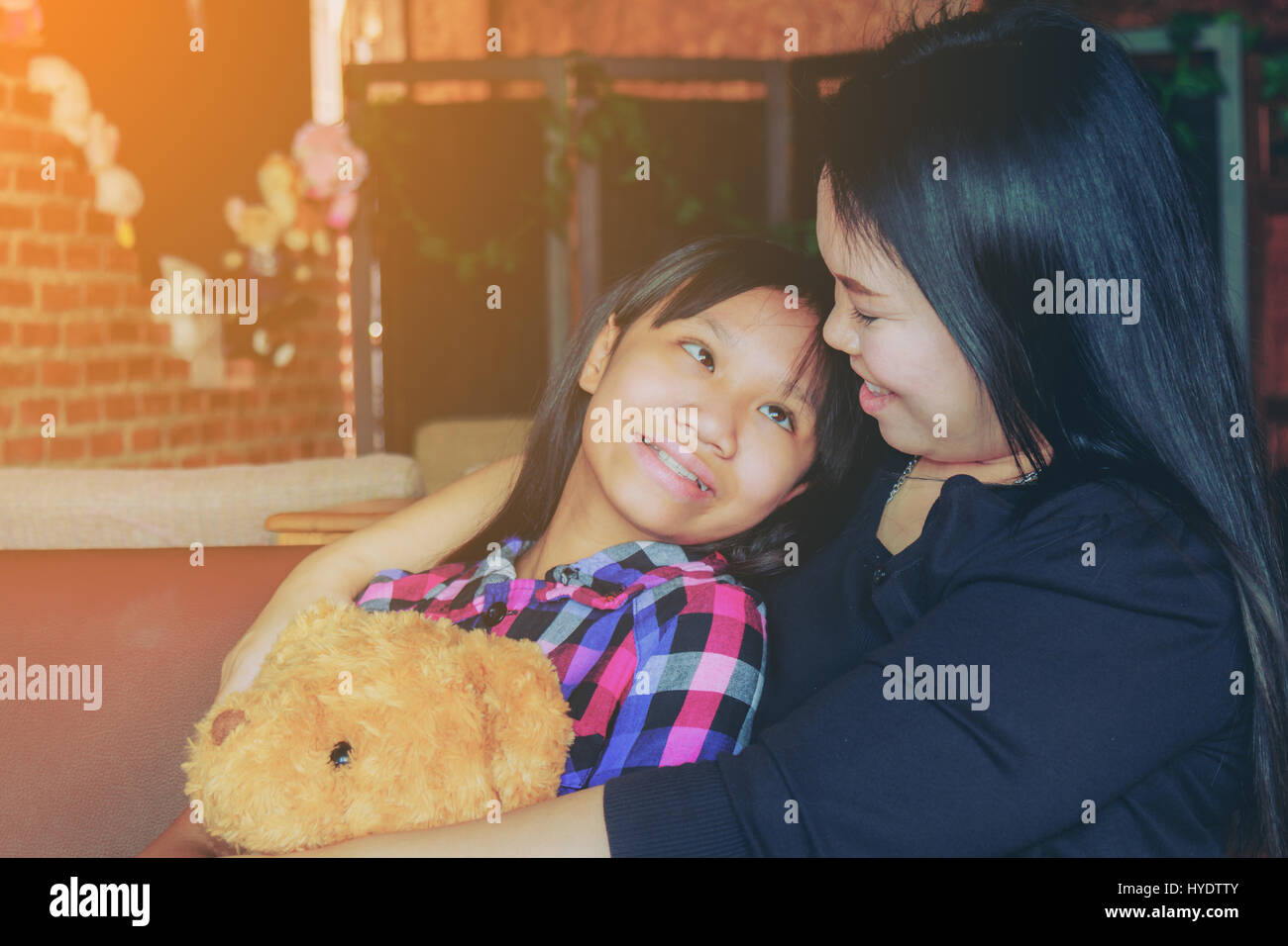 Mutter und Tochter hug Teddy Bear im Beall liebevoll. Tiefenschärfe und weiche Flare Sonnenlicht. Stockfoto