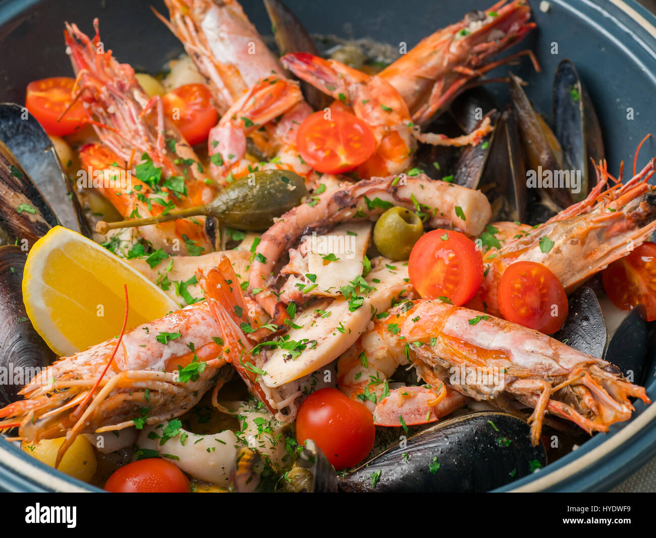 Bunte frische Meeresfrüchte mit Gemüse und Gewürzen auf blaue Platte im Restaurant. Nahaufnahme Stockfoto
