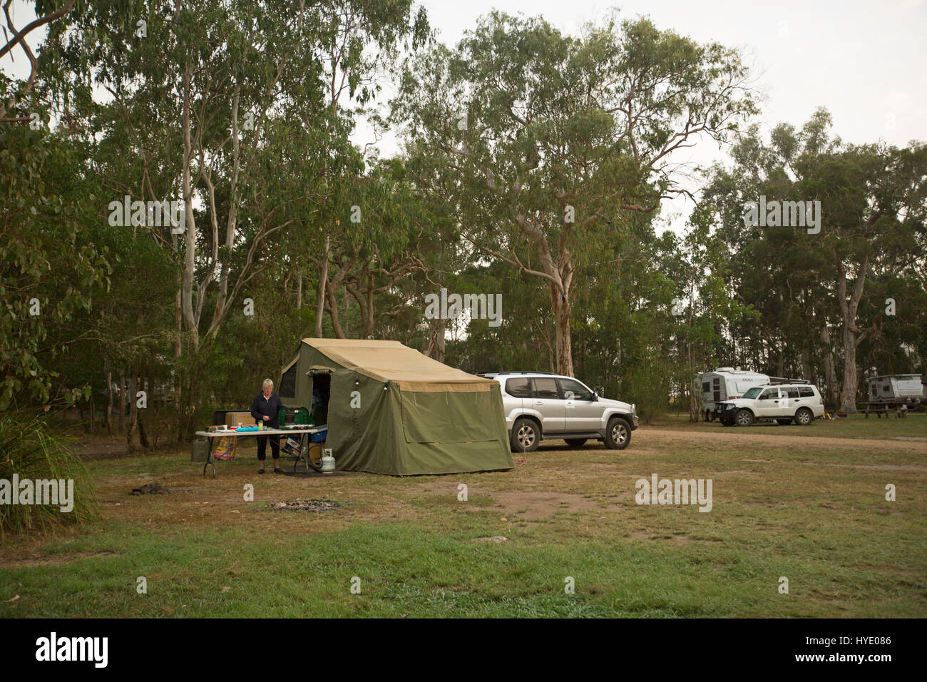 Campertrailer und Allrad Fahrzeuge fahren auf Campingplatz kostenlos Buschland mit Frau arbeitet am Gartentisch in New South Wales Australien Stockfoto