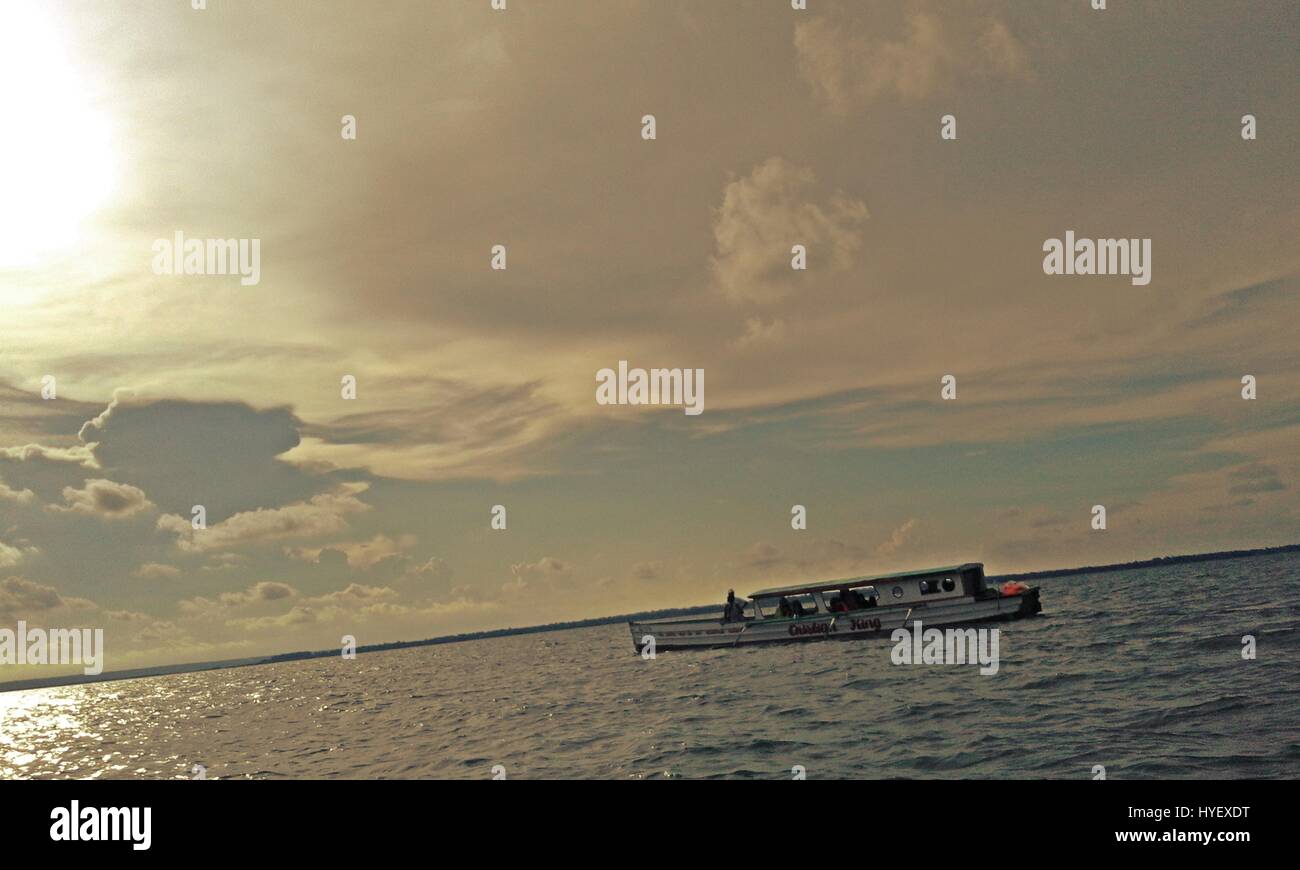 Ein Boot mit Passagieren auf dem Meer mit Wolke Bildung Hintergrund Stockfoto