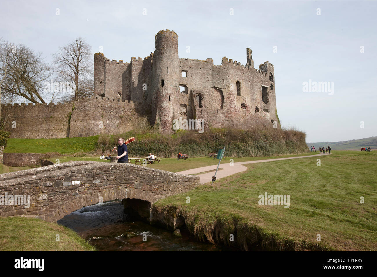 Ein Mann ging mit einer Gitarre in der Hand über eine Brücke von Laugharne Castle, The Literary Festival, Laugharne, Wales, Uk Stockfoto