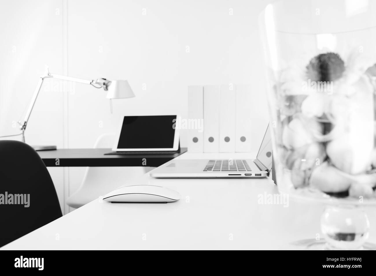Moderne Büro-Arbeitsplatz mit Notebook und Smartphone, digital-Tablette Docking-Tastatur, Glas Vase Blume, schwarz und weiß Stockfoto