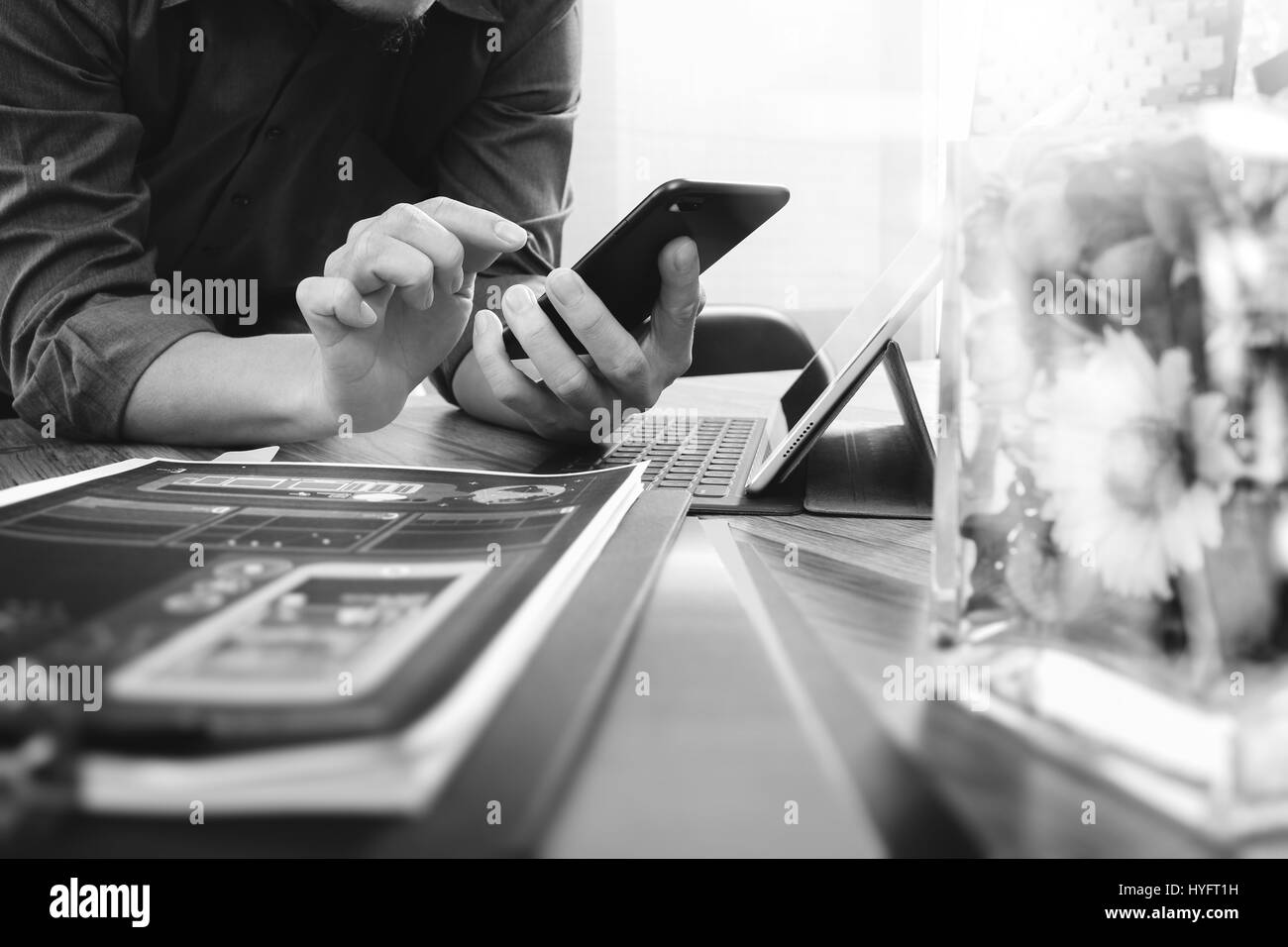 Geschäftsmann Hand mit Smartphone, mobile Zahlungen online-shopping, Omnichannel, digital-Tablette Docking-Tastatur Computer, Glas Blumenvase auf hölzernen d Stockfoto