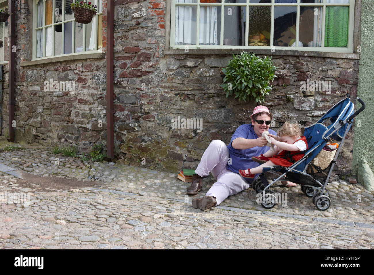 Erwachsenen und ein Kind saß in einem Kinderwagen entspannend auf der Straße, das Literaturfestival, Laugharne, Wales, Uk Stockfoto