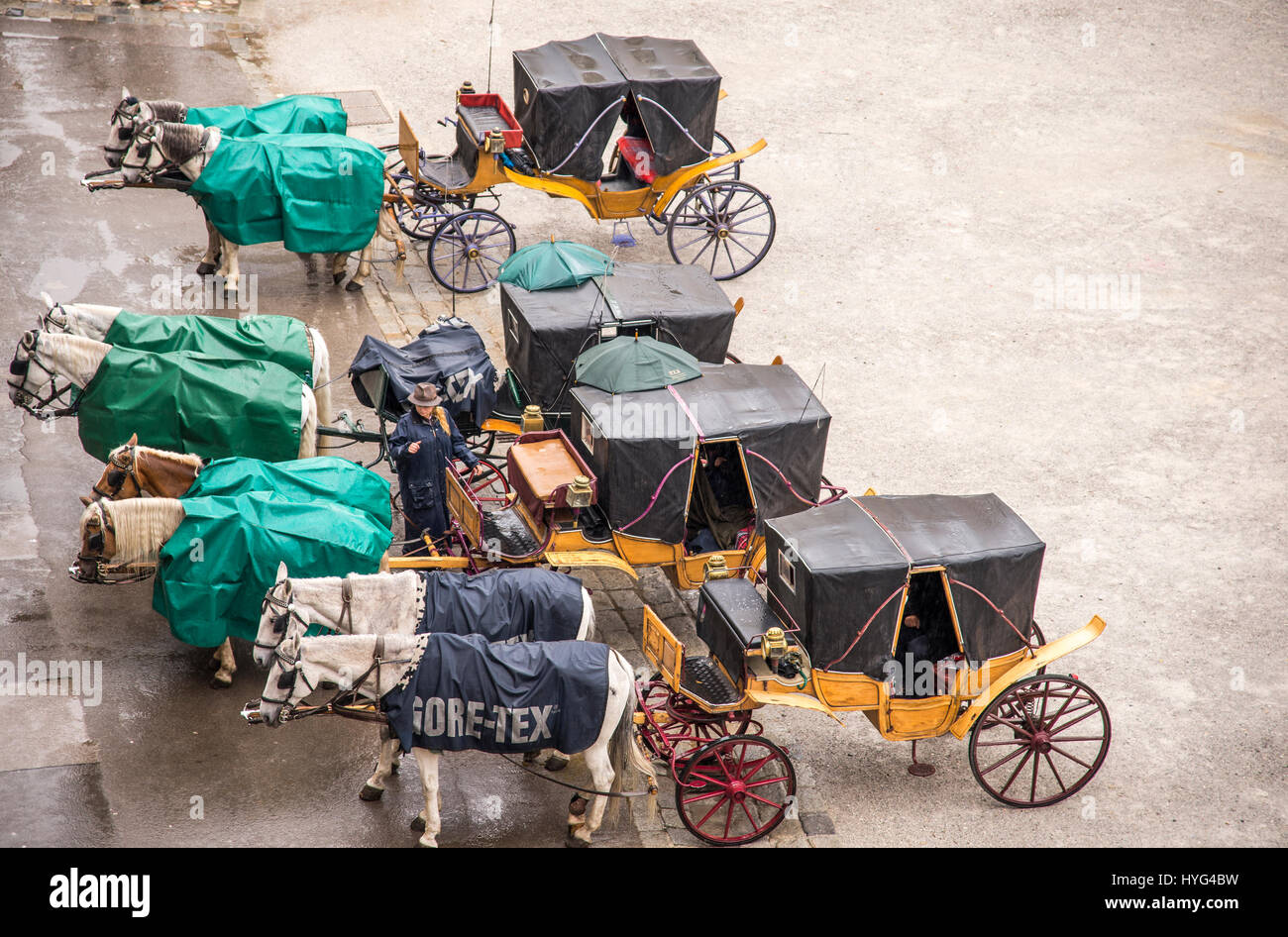 Pferdekutschen warten auf Touristen an einem regnerischen Tag in Salzburg Österreich. Die Pferde sind in wasserdichte decken bedeckt. Stockfoto