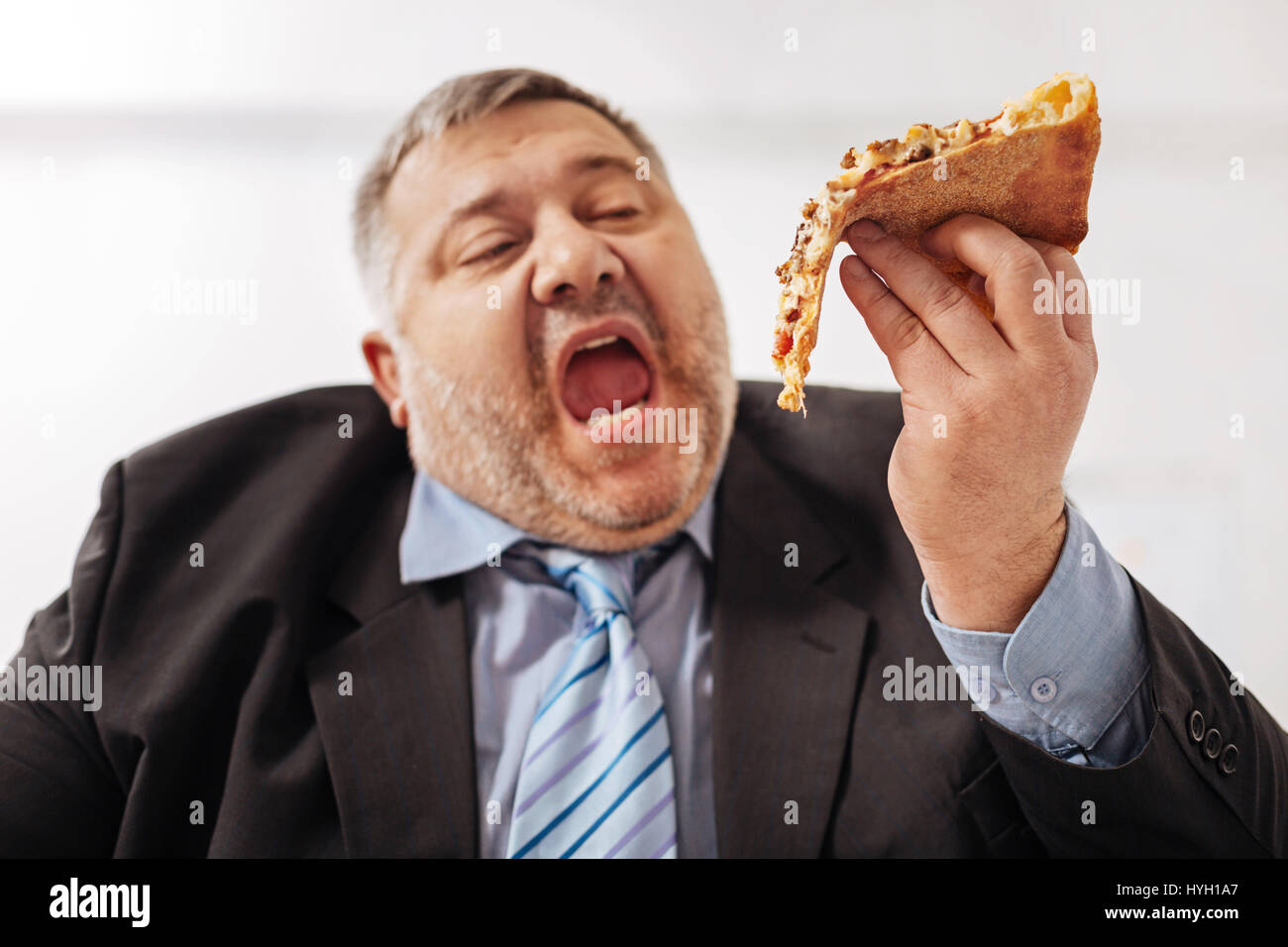 Fanatische übergewichtige Mann beißt ein Stück pizza Stockfoto