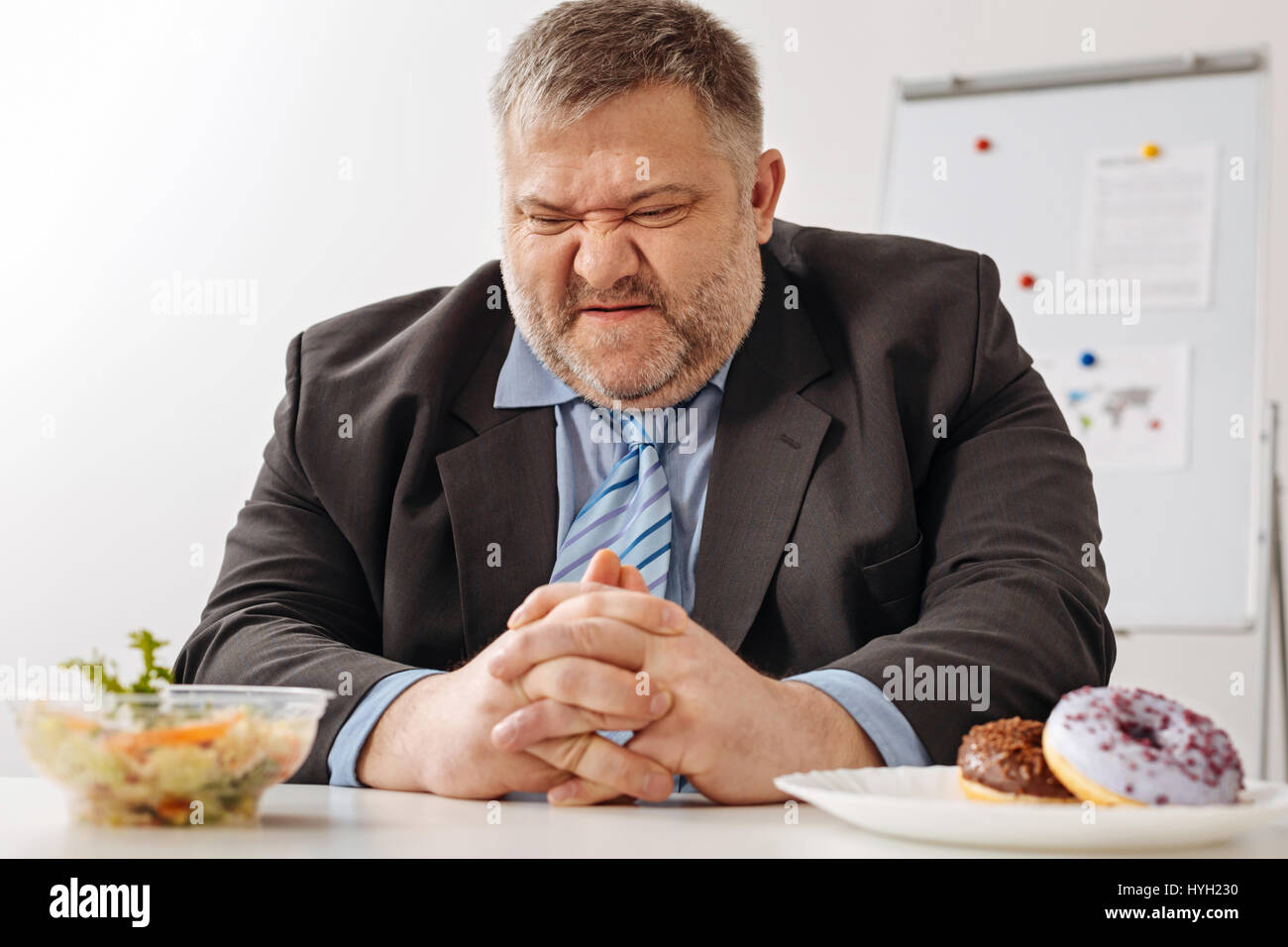 Humorvolle pummeligen Mitarbeiter unglücklich über seine neue Diät Stockfoto