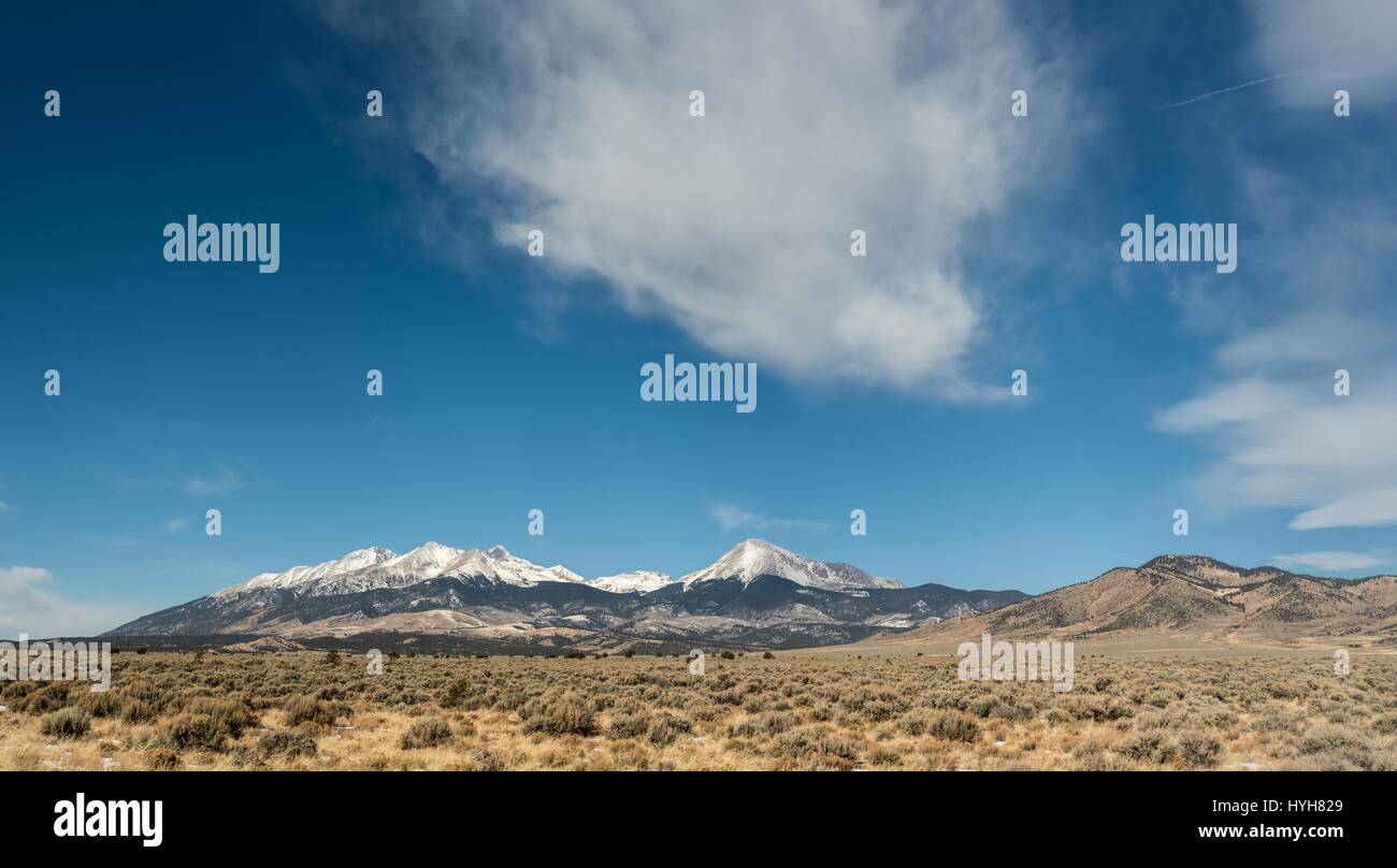Panorama von Schnee bedeckt Bergkette hinter einem offenen Feld Stockfoto