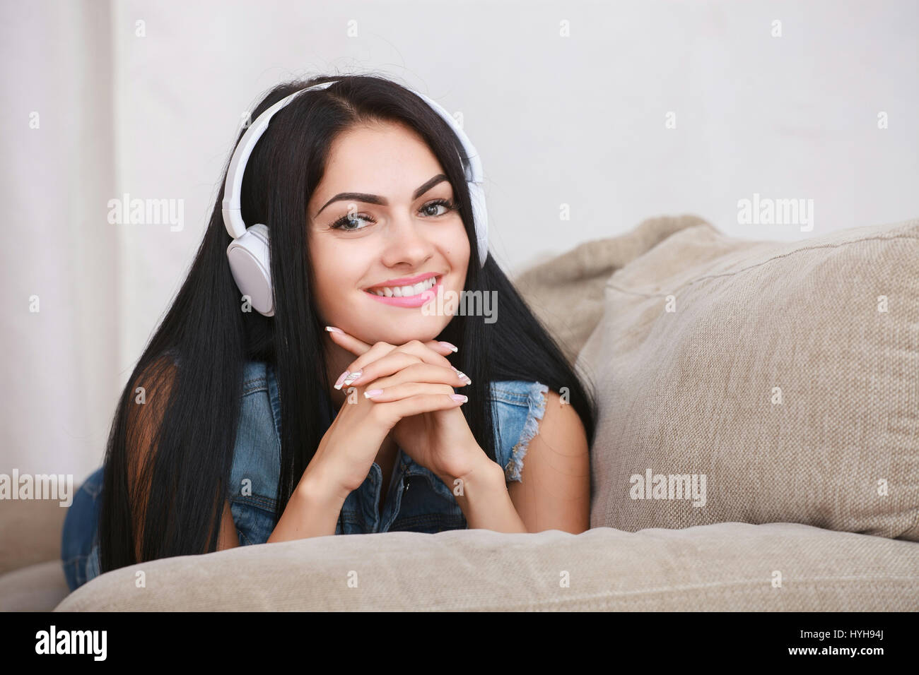 Frau Musik hören Kopfhörer sitzt auf dem Sofa im Zimmer Stockfoto