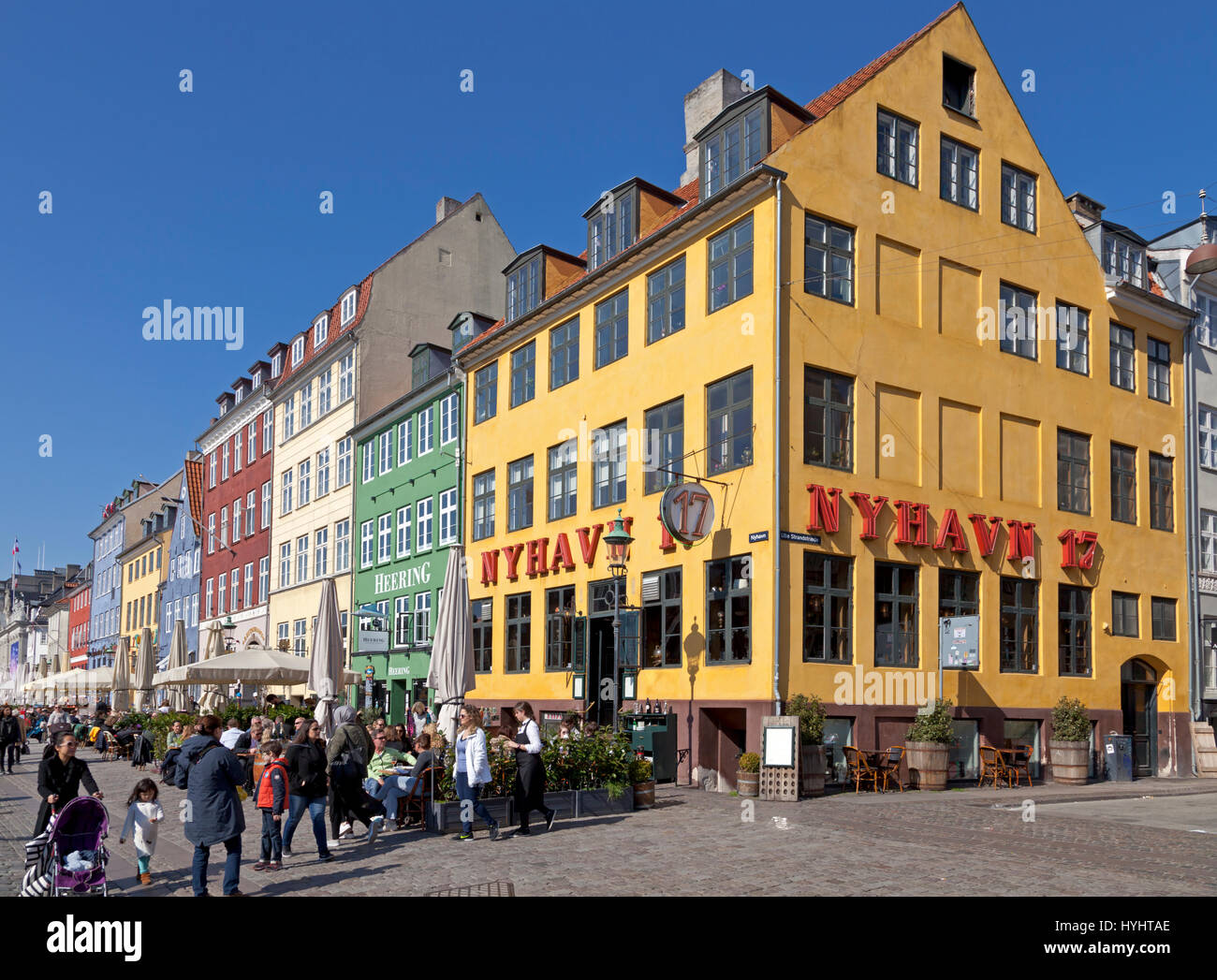 Die Hafenrestaurants in Nyhavn, Kopenhagen, Dänemark, locken viele Kopenhagener und Touristen an einem sonnigen Frühlingstag Anfang April Stockfoto