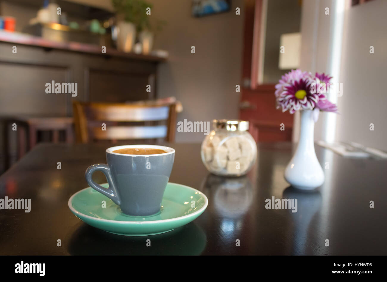 Einfache Tasse Espresso mit Würfel Zucker und eine Blume auf einem Holztisch. Stockfoto