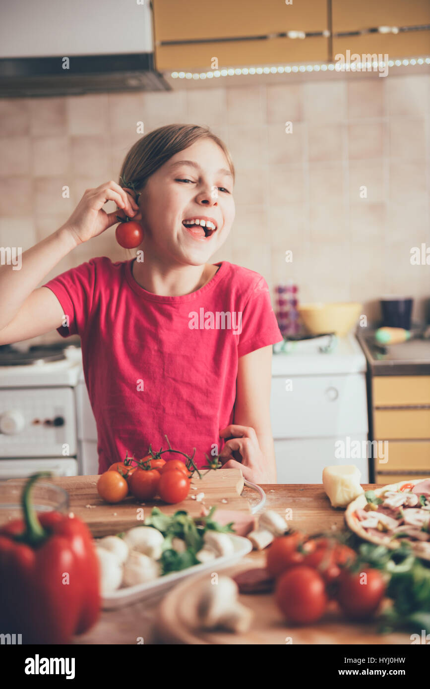 Niedliche kleine Mädchen herumalbern mit Tomaten in der Küche Stockfoto