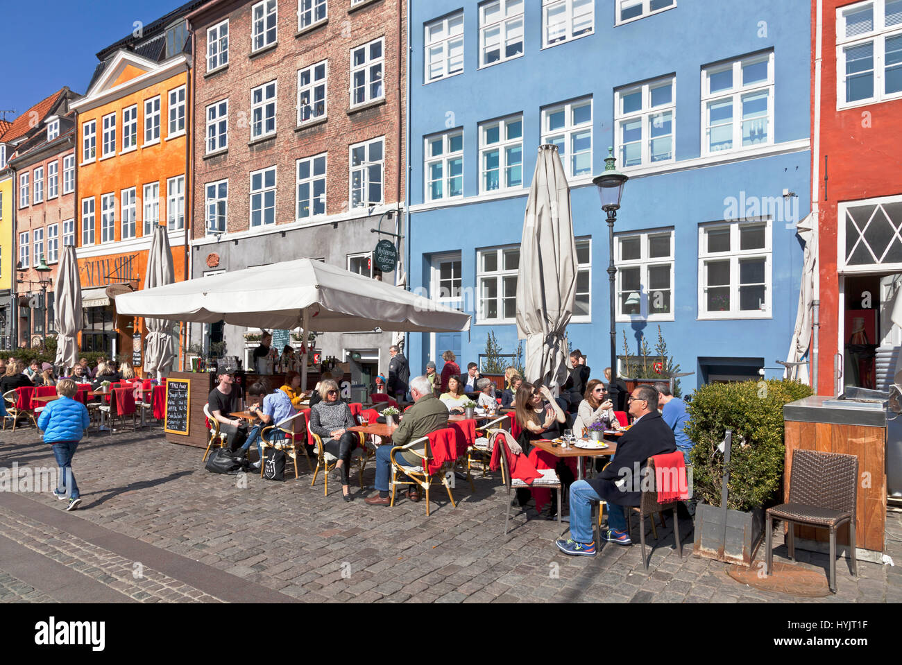 Die historischen Hafenrestaurants in Nyhavn, Kopenhagen, Dänemark, locken viele Kopenhagener und Touristen an einem sonnigen Frühlingstag Anfang April Stockfoto