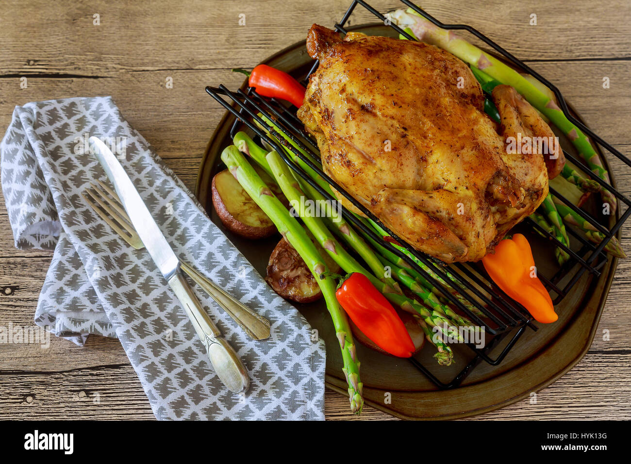 Goldene knusprige Haut Huhn gegrillt im Ofen mit Kartoffeln und Lauch in gusseisernen Pfanne auf alte Holzbretter, Schneidebrett mit Scheiben von Zwiebeln und Stockfoto