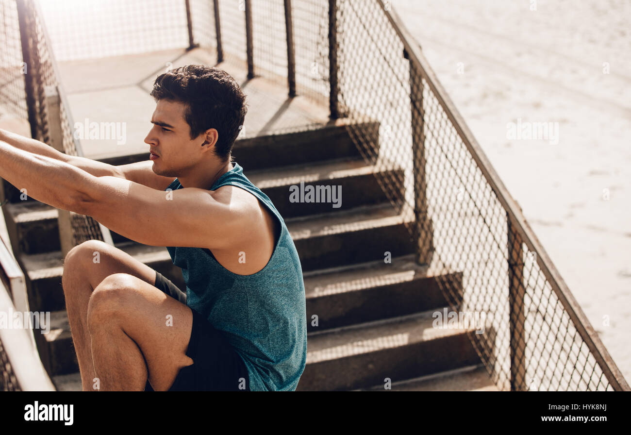 Fitness, Männlich stretching Training im Freien am Strand zu tun. Gesunde junge Mann erstreckt sich auf einem Geländer. Stockfoto