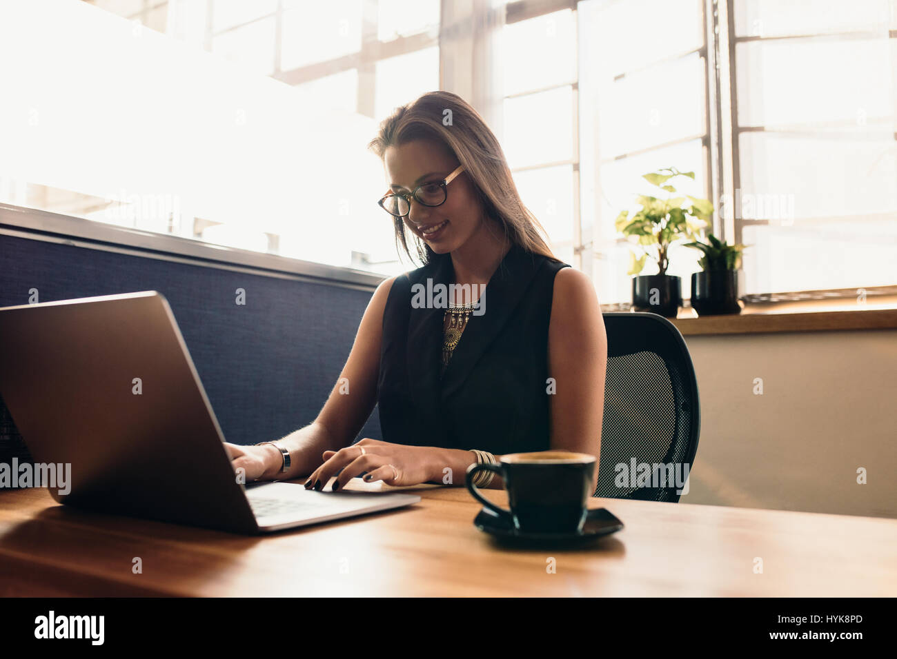 Weibliche Vloggerin ihr Vlog am Computer bearbeiten. Junge Frau an ihrem Schreibtisch im Büro arbeiten am Computer mit einer Tasse Kaffee. Stockfoto