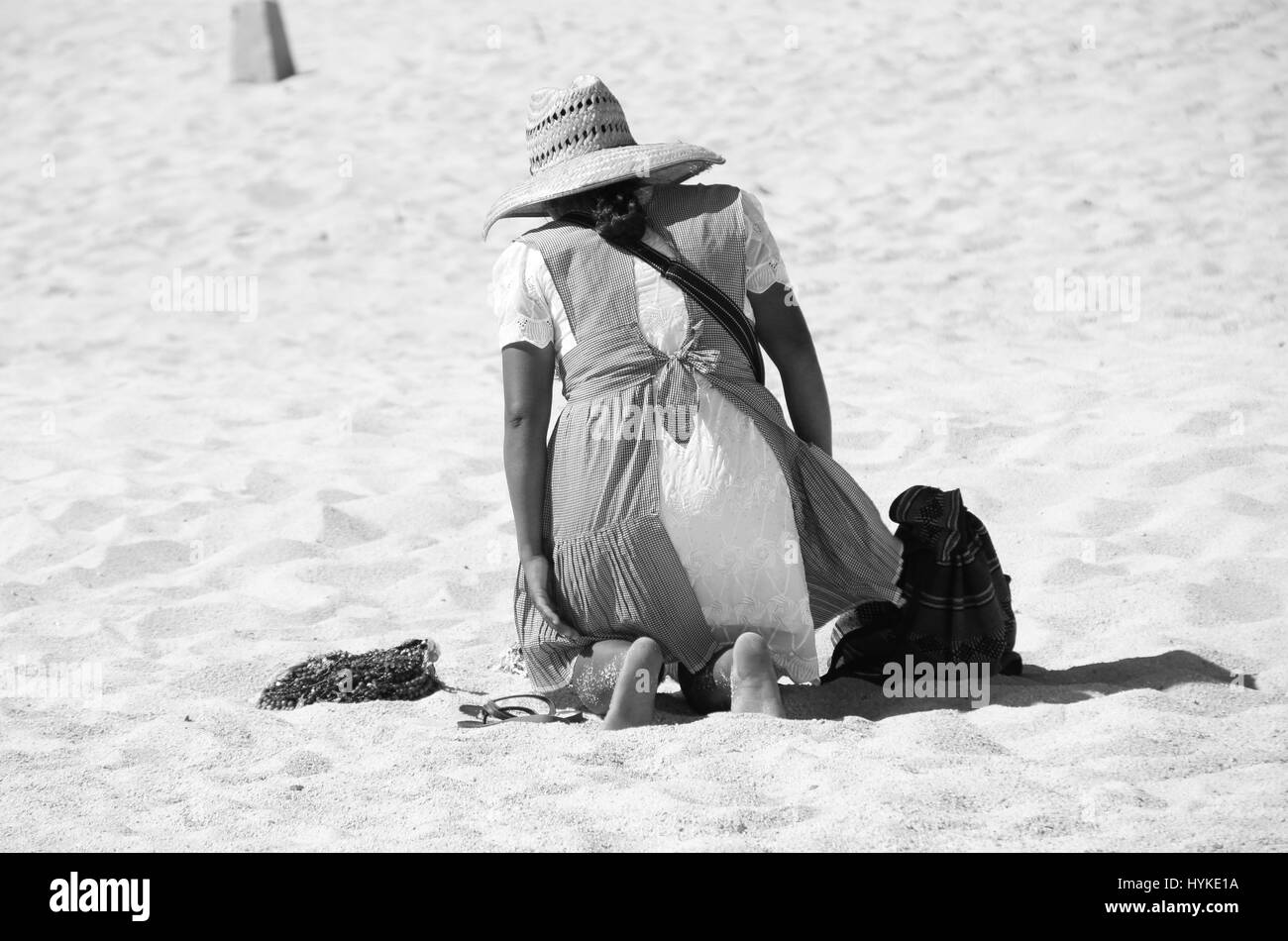 Hart arbeitenden Frau in traditioneller Kleidung, kniend im Sand um ihre waren an einem heißen sonnigen Morgen zum Verkauf bereit. Stockfoto