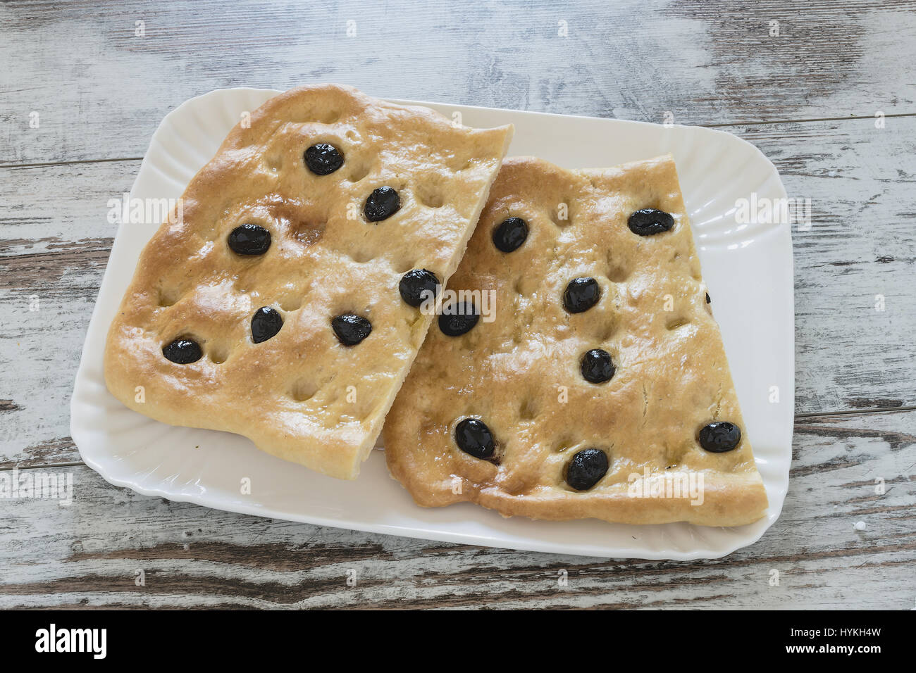 Focaccia mit Oliven halbieren auf einem weißen Keramik Tablett Stockfoto