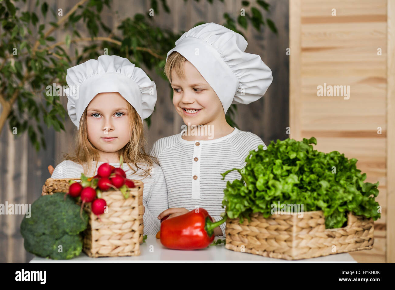 Hübscher Junge und schöne junge Mädchen spielen in der Küchenchefs. Gesunde Ernährung. Gemüse Stockfoto