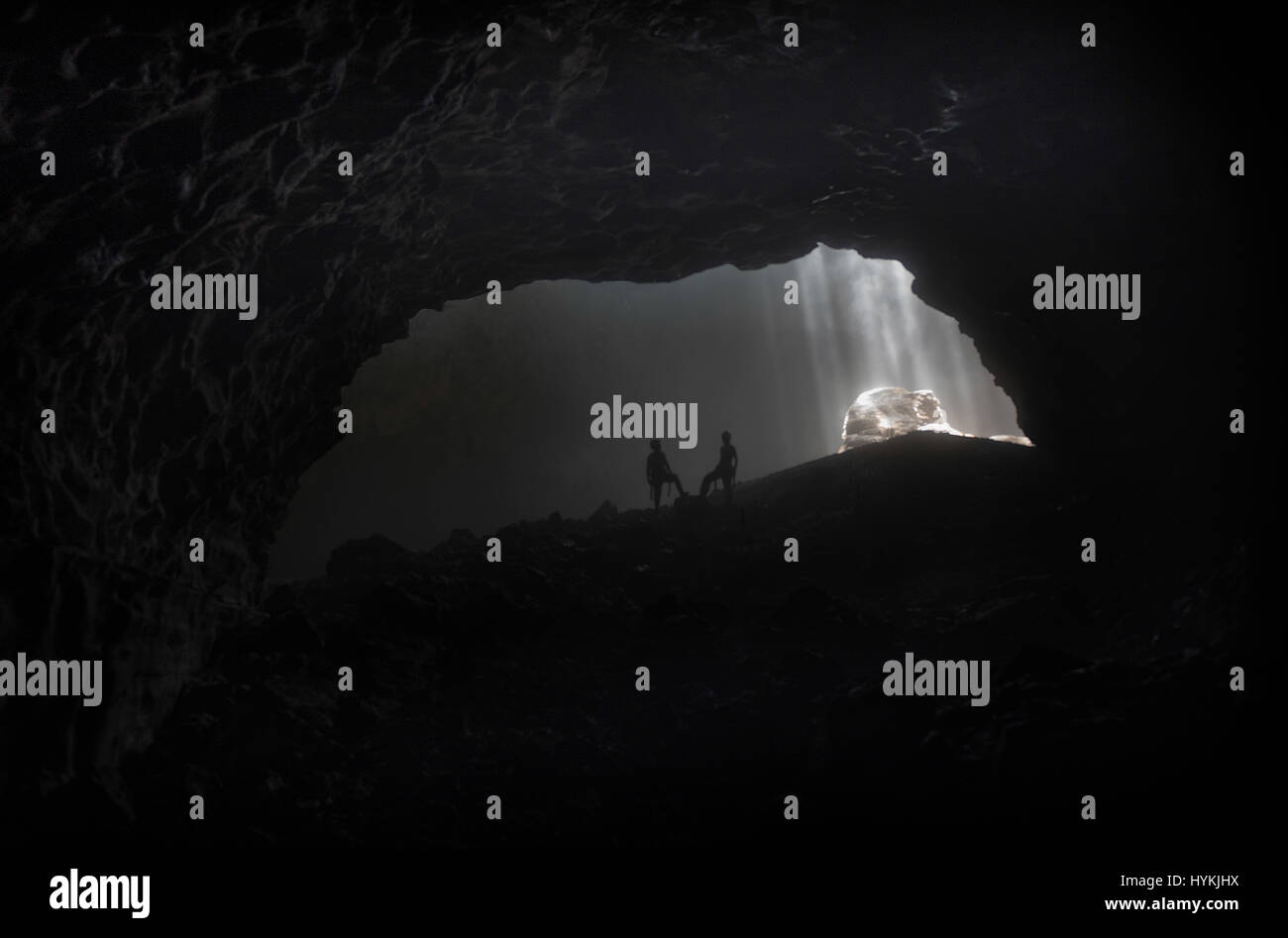 YOGYAKARTA, Indonesien: Unglaubliche Abseilen Bilder aus einer dreihundert Fuß hohe vertikale Höhle mit einer dunklen Geschichte wurden von Mann und Frau Team gefangen genommen. Bilder und Videos zeigen das Ausmaß des Aufstiegs in die schwarze Höhle, hervorgehoben durch Sonnenstrahlen, die durch den Mund der Höhle lugt. Das unheimliche Abseilen in die schwarzen fand in Indonesiens Jomblang Höhle, synchronisierte Massaker Höhle aufgrund seiner schrecklichen Vergangenheit wo in 1965 Hunderte von Mitgliedern der PKI, kommunistische Partei von Indonesien, wurden angeblich und massakriert.  Geschichten rund um diese Höhle noch spuken die Dorfbewohner ein Stockfoto