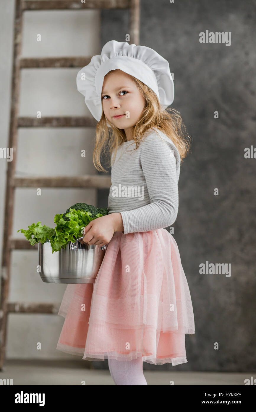 Schöne Mädchen hält einen Topf voll mit Gemüse. Gesunde Ernährung. Ernte. Kleine Hausfrau Stockfoto