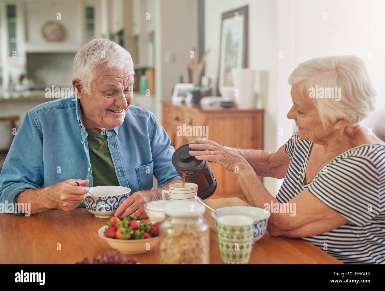 Lächelnde senior Frau Gießen ihr Ehemann einen Kaffee beim Frühstück Stockfoto