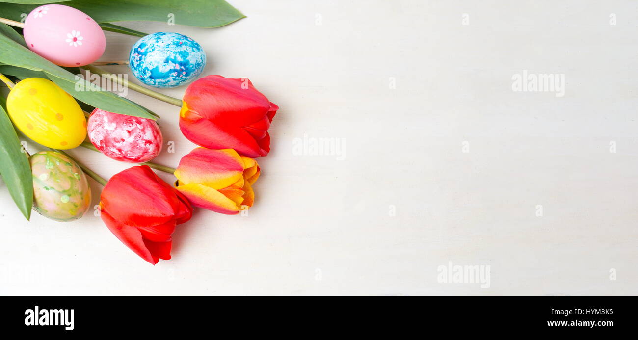 Rote Tulpen und bemalte Ostereier auf Holztisch Stockfoto