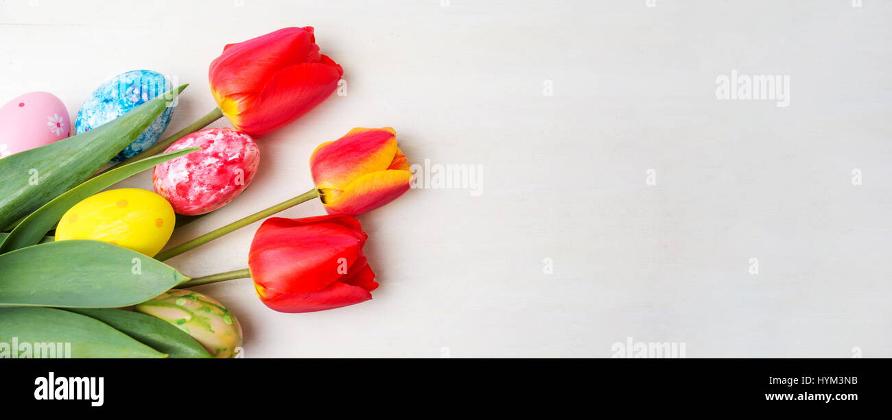 Rote Tulpen und bemalte Ostereier auf Holztisch Stockfoto