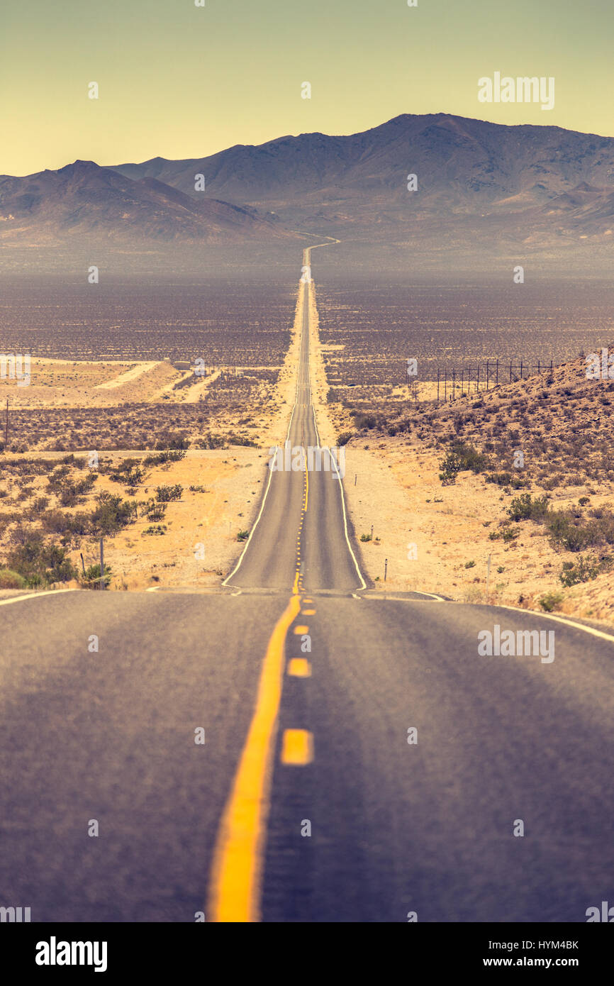 Klassische vertikale Ansicht einer endlosen geraden Straße laufen durch die karge Landschaft des berühmten Death Valley mit extremer Hitze Dunst an einem sonnigen Tag Stockfoto Klassische vertikale Ansicht einer endlosen geraden Straße laufen durch die karge Landschaft des berühmten Death Valley mit extremer Hitze Dunst an einem sonnigen Tag Stockfoto