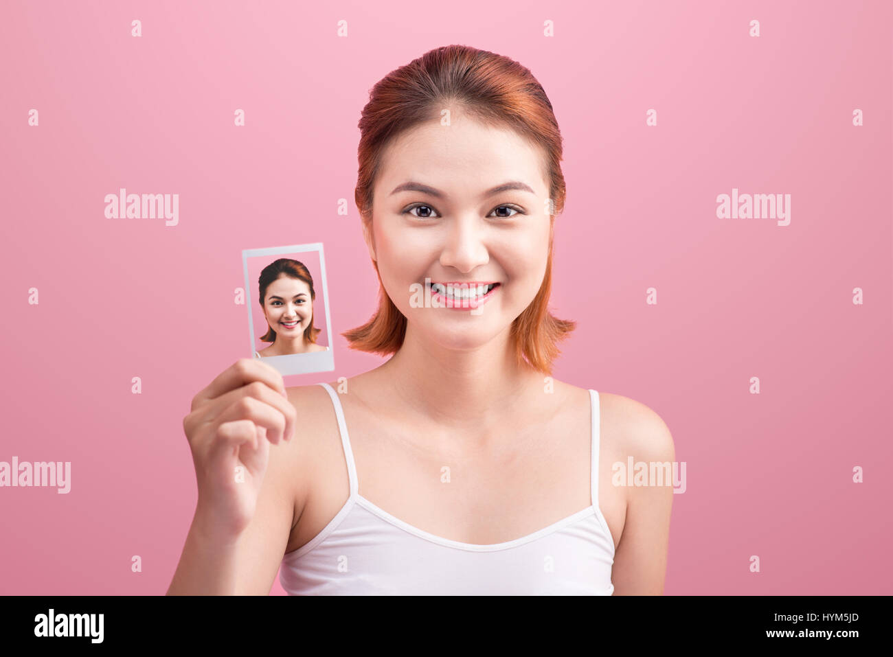 Junge asiatische Frau hält ihr Bild auf rosa Hintergrund. Stockfoto