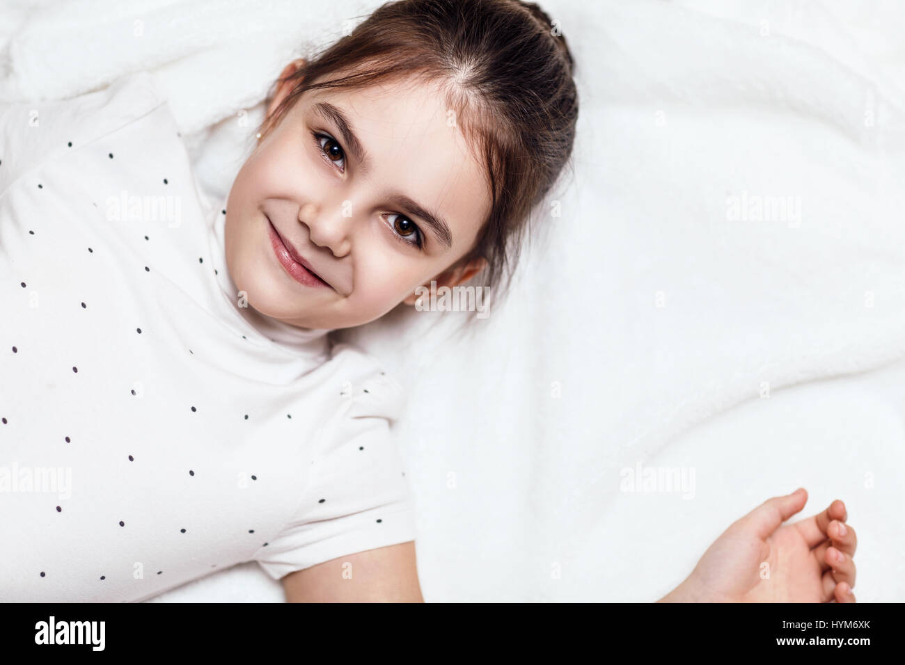 Draufsicht auf niedliche Brünette Mädchen auf dem Bett liegend. Stockfoto