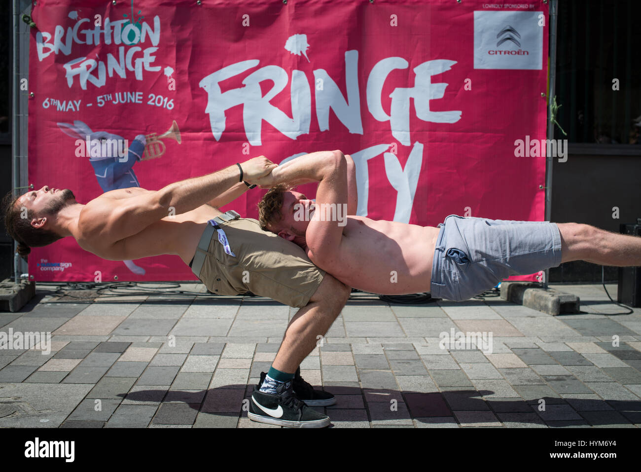 Ein männlicher Acrobat hält seinen Freund in der Luft während eines Straße Leistung im Brighton Fringe in Brighton, East Sussex, UK, England. Stockfoto